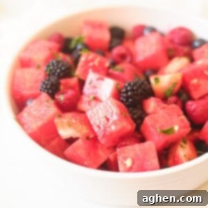 A vibrant bowl of watermelon berry salad, garnished with fresh mint.