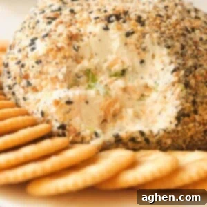 The Everything Bagel Cheese Delight 2 Everything Bagel Cheese Ball with crackers on a white plate, ready to serve.