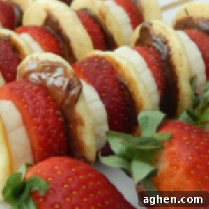 Close-up of a breakfast kabob featuring mini pancakes, strawberries, and banana slices.