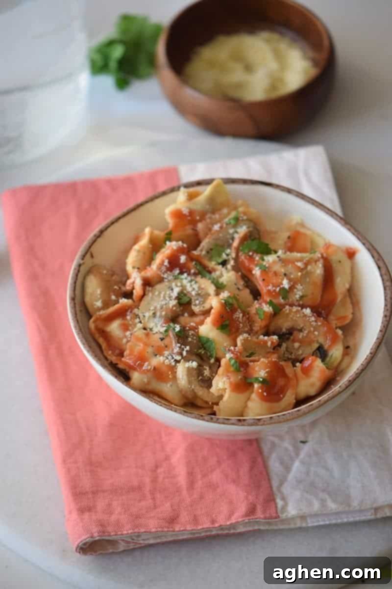 Savory Mushroom Ragu 4 Bowl of ravioli with mushroom pasta sauce and bowl of Parmesan cheese in the background.