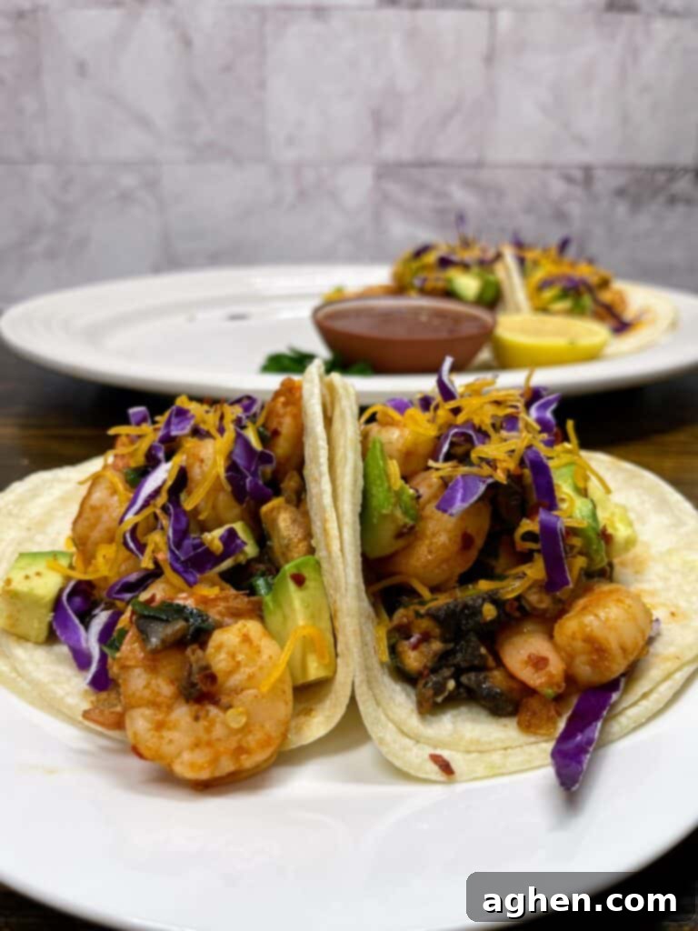 Two vibrant chipotle shrimp tacos with avocado and cilantro