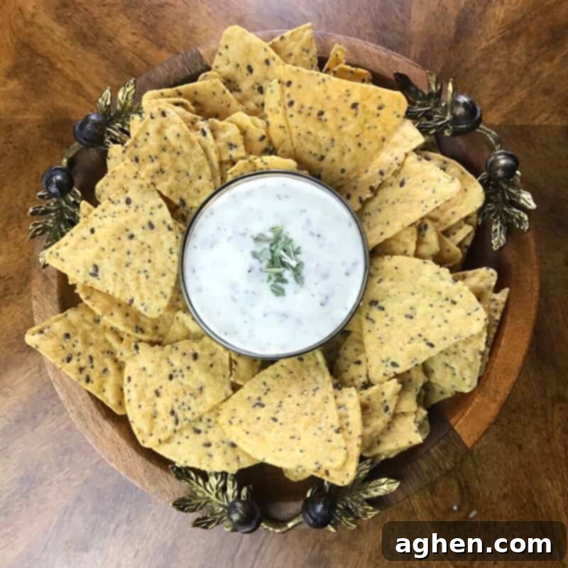 Creamy bacon ranch dip in a rustic bowl, perfectly garnished with fresh basil, surrounded by a vibrant assortment of colorful tortilla chips, making it an ideal easy appetizer for any gathering or game day event.