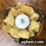 Round platter with a bowl of bacon ranch dip in the center, surrounded by crispy tortilla chips, creating an inviting appetizer spread.