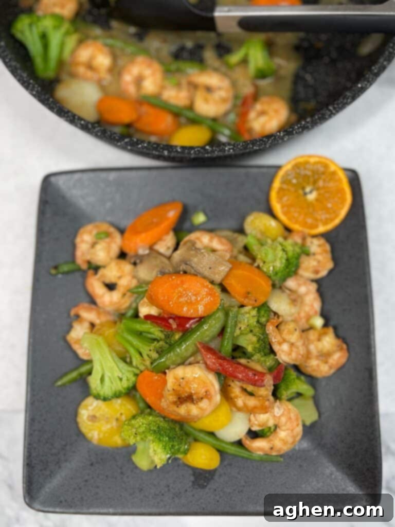 Cooked Weight Watchers shrimp stir fry with an orange slice garnish on a white plate