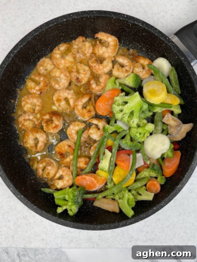 Shrimp and vegetables combined and cooking in a stir fry pan