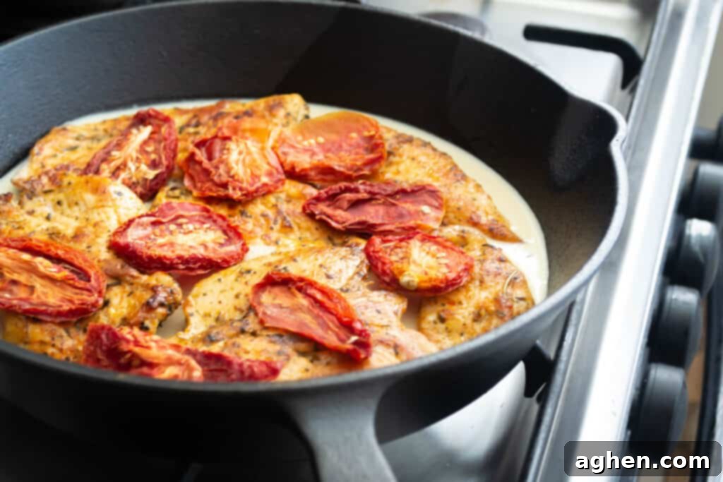 tuscan chicken cooking in pan with sauce and ingredients