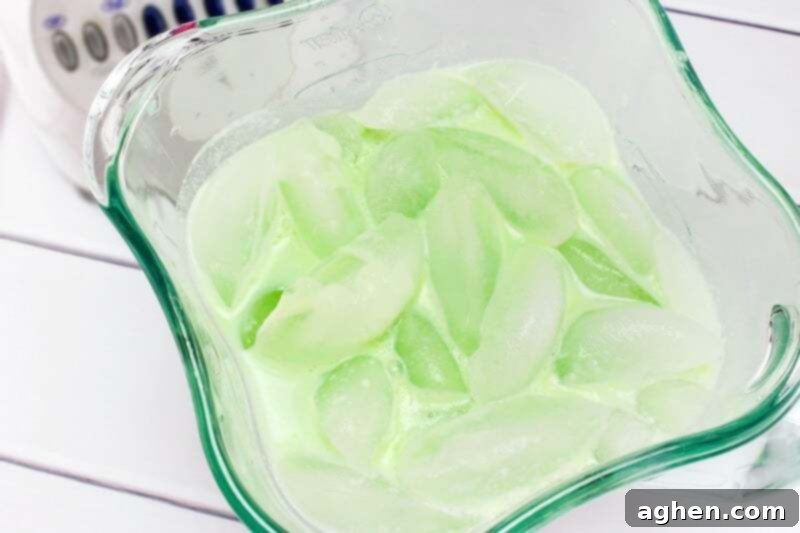 Green liquid and ice in blender.
