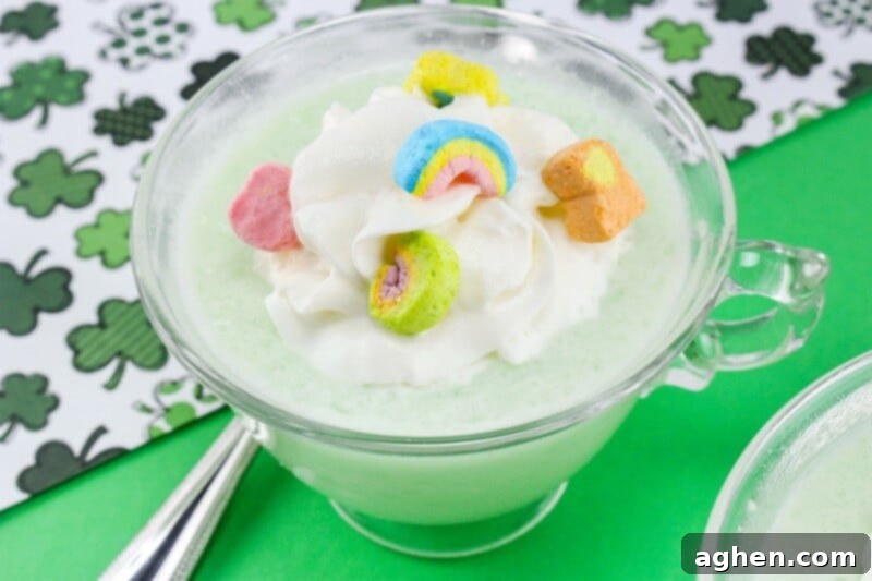 Green frozen drink in glass mug topped with whipped cream and lucky charms marshmallows.