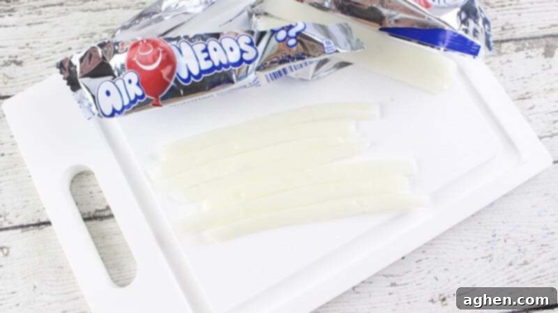 Half inch long strips of white airhead candy on cutting board.