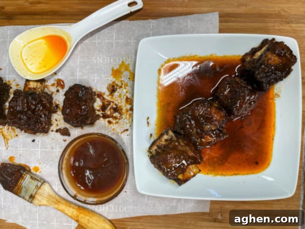 Close-up of cooked bone-in beef short ribs coated in rich BBQ sauce and garnished with fresh herbs