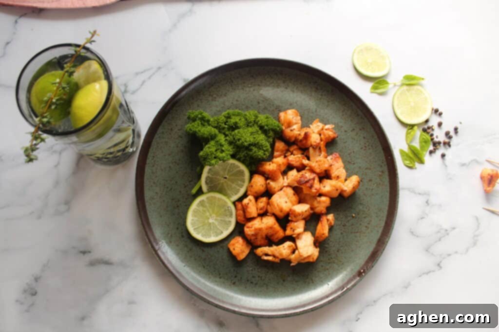 Plated air fryer salmon bites with fresh lime wedges and chopped parsley garnish