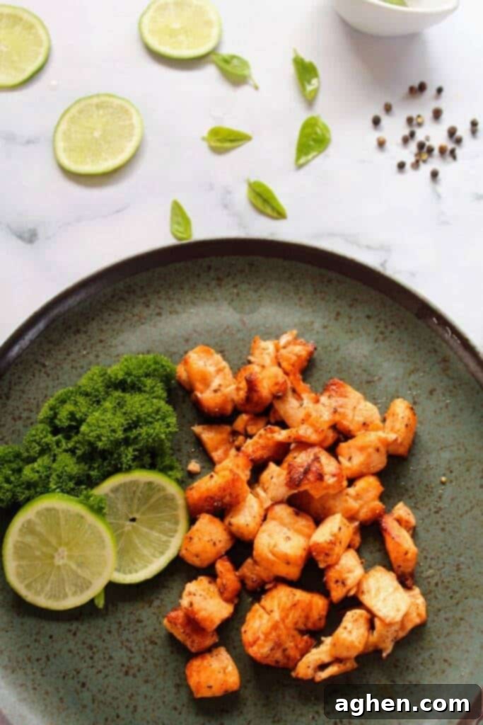 Cooked chili and lime salmon bites plated beautifully with a fresh lime wedge and fresh herbs