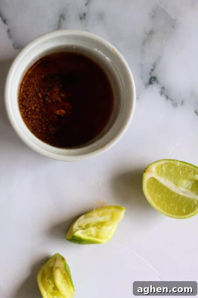 Close-up of lime, olive oil, chili powder, and dried basil mixed in a small bowl, creating a flavorful marinade
