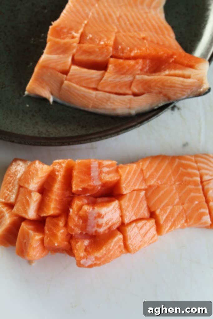 Raw salmon filets expertly diced into uniform ½ inch cubes on a clean cutting board
