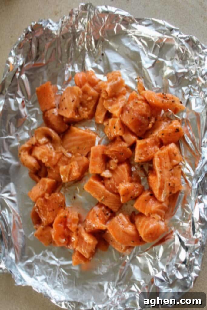 Diced raw salmon seasoned with chili and lime, spread evenly on tin foil, ready to be placed in the air fryer