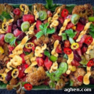 Loaded Cauliflower Nachos 2 Cauliflower Nachos on a green plate, garnished with fresh cilantro and chili peppers