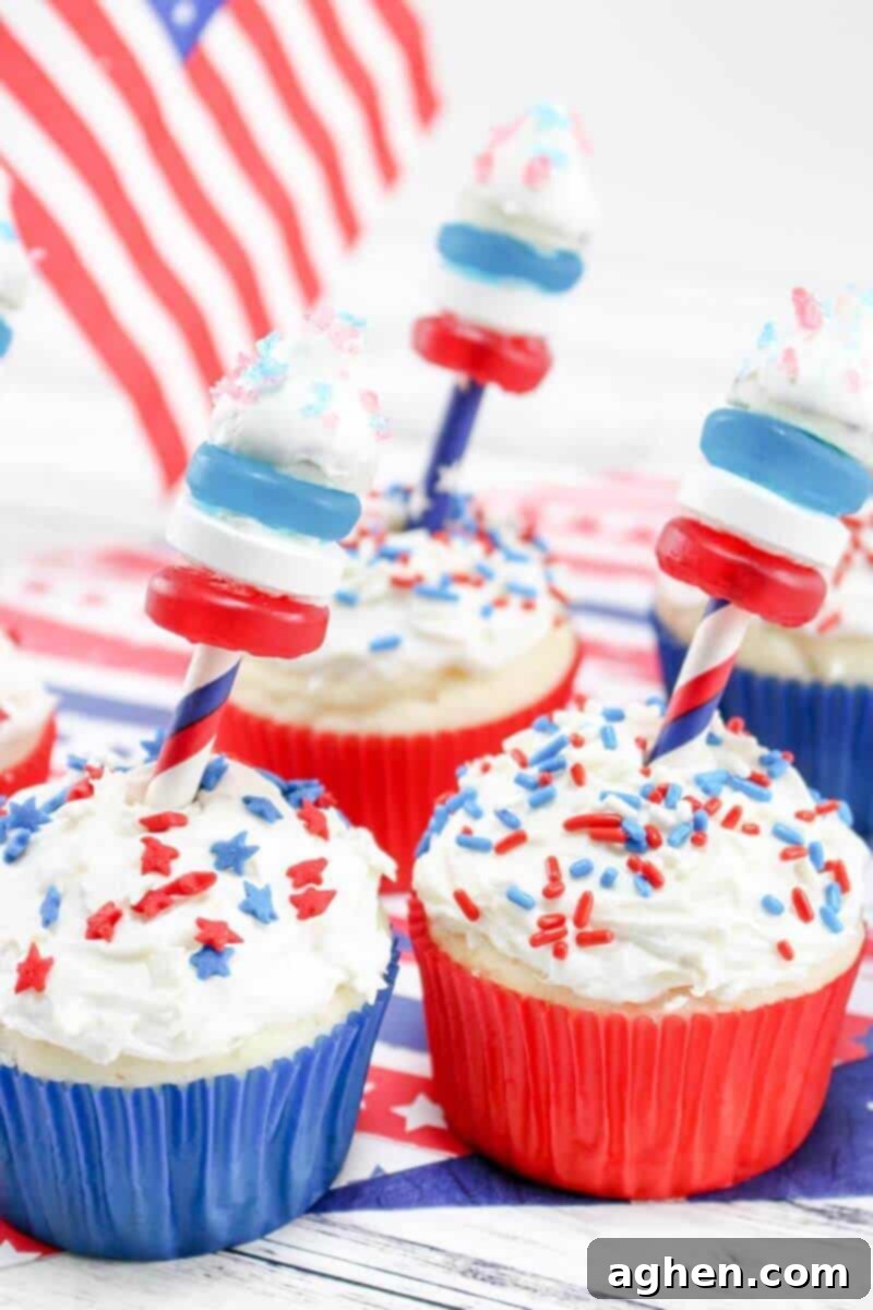 Red, white, and blue cupcakes with firecrackers made of life saver gummies, Hershey kisses, paper straws, and pop rocks coming out the top of them, creating a festive 4th of July display.