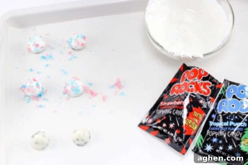 Close-up of Pop Rocks popping candy being carefully sprinkled on top of white Hershey kisses that have been dipped in melted white chocolate.