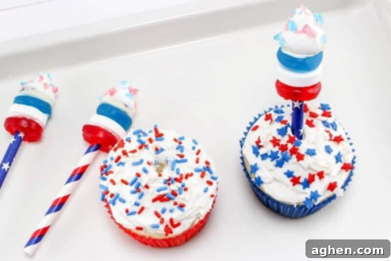 A hand gently pushing a completed candy firecracker cupcake topper into the center of a frosted cupcake, ready for serving.