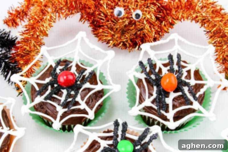Close-up of chocolate frosted cupcakes featuring intricate white candy melt spider webs and playful chocolate M&M spiders.