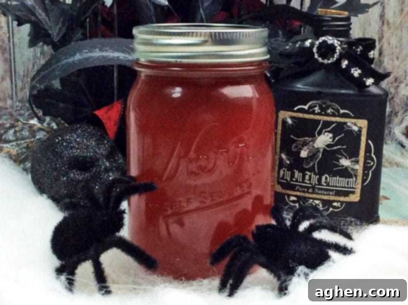 Crimson Silk Spirit 2 Dark red Black Widow Venom Moonshine in a mason jar, elegantly surrounded by spooky Halloween decorations including black flowers, a decorative skull, and fuzzy spiders, enhancing its ominous and festive appeal.