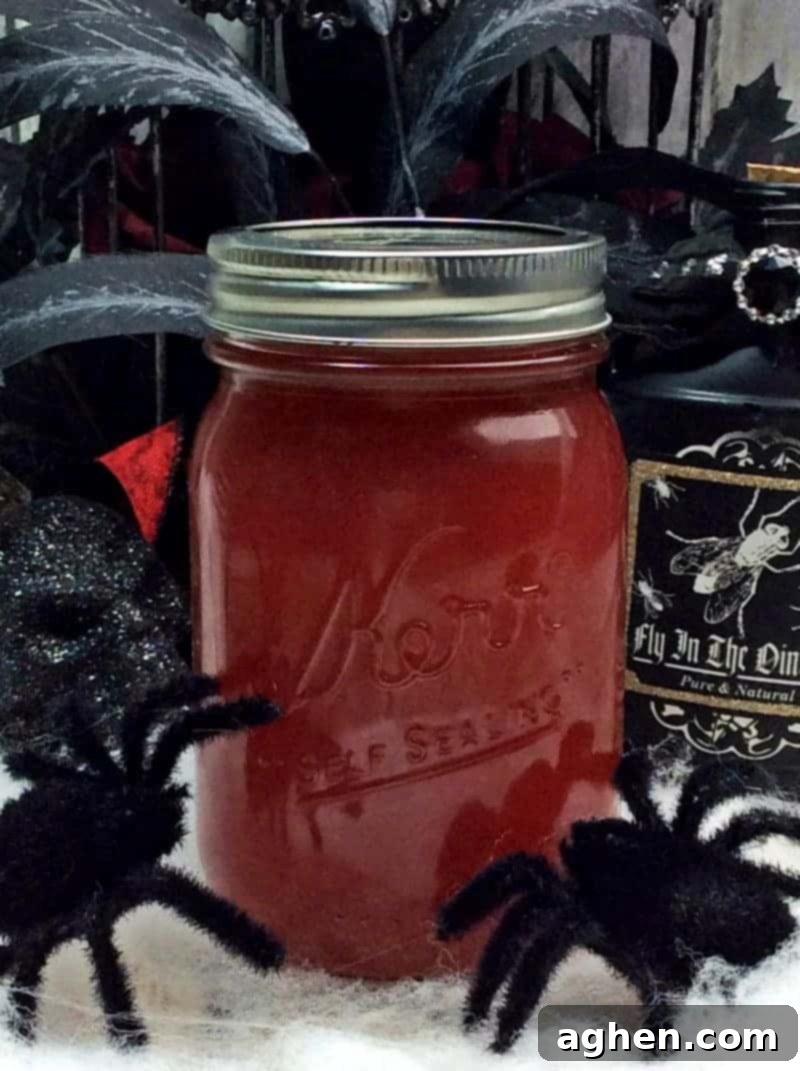 Crimson Silk Spirit 3 A securely sealed mason jar filled with vibrant Black Widow Venom Moonshine, prominently displayed amidst an array of Halloween-themed decor, including cobwebs and dark foliage, highlighting its festive appeal and readiness for infusion.