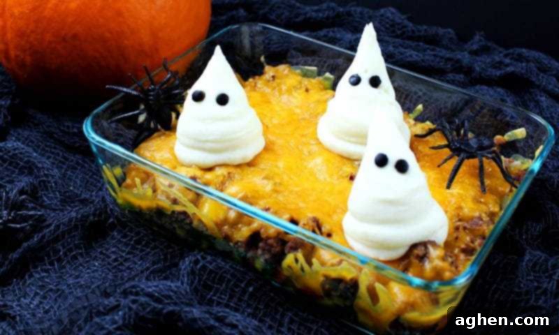 Halloween dinner casserole topped with mashed potato ghosts and plastic spider decorations, ready to be served.