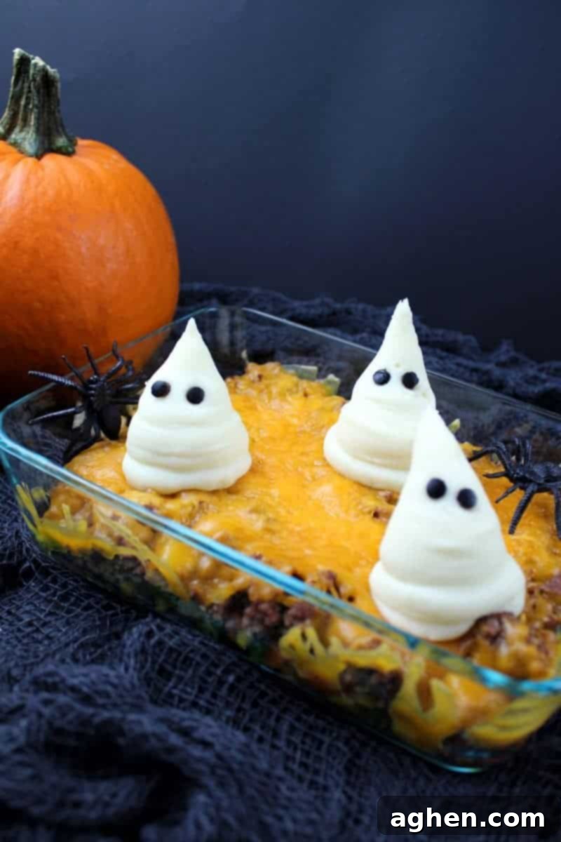 Close-up of Haunted Shepherd's Pie in a glass baking dish with ghosts made from mashed potatoes on top, showcasing the detail of the olive eyes.