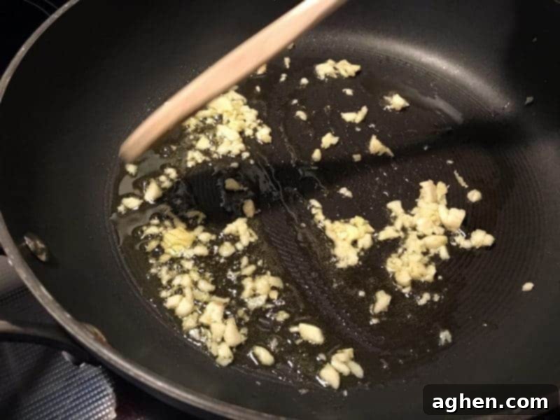 Minced fresh garlic sizzling in olive oil in a frying pan.