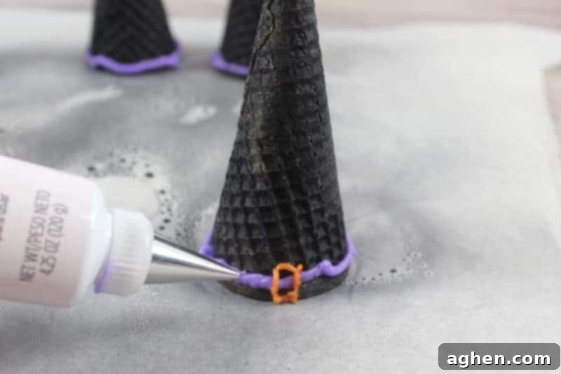 Spooky Witch Hat Cupcakes 10 Upside down black ice cream cones being drawn on with tube of purple icing gel to form a ribbon.