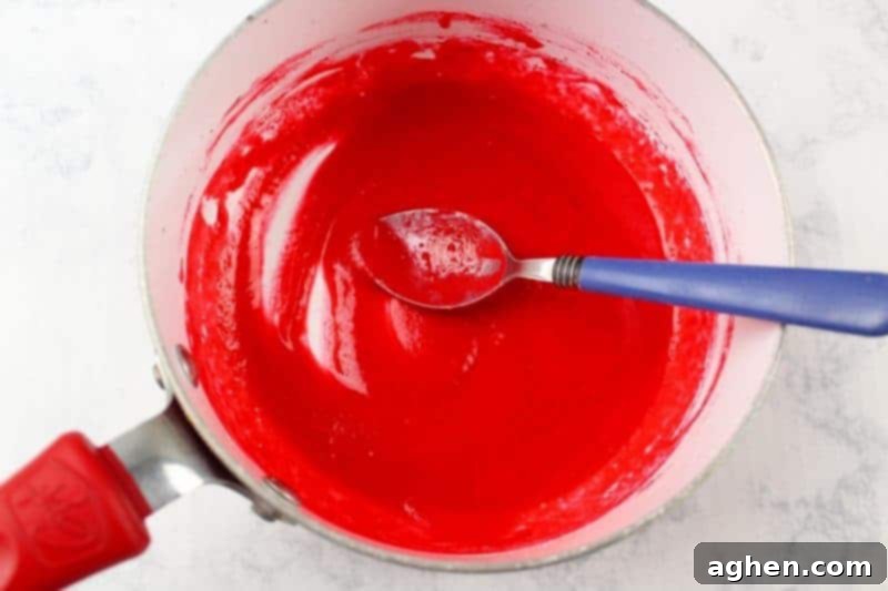Red melted chocolate in a small pot on the stove, ready for creating the bloody splatter effect on the Halloween bark.