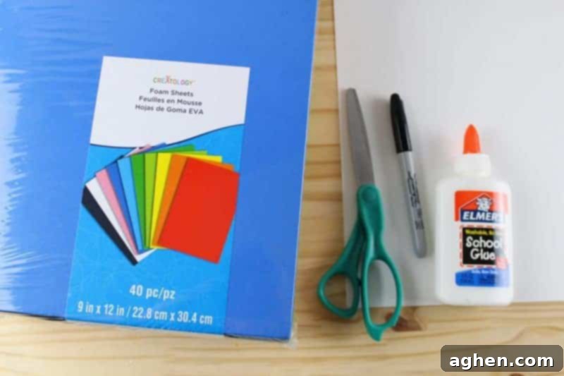 A collection of essential craft supplies including colorful craft foam sheets, child-safe scissors, and glue, ready for alphabet crafting.