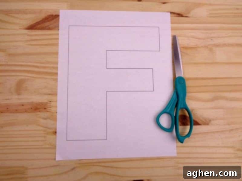 Cutting out the printable uppercase Letter F template from a sheet of paper with scissors.