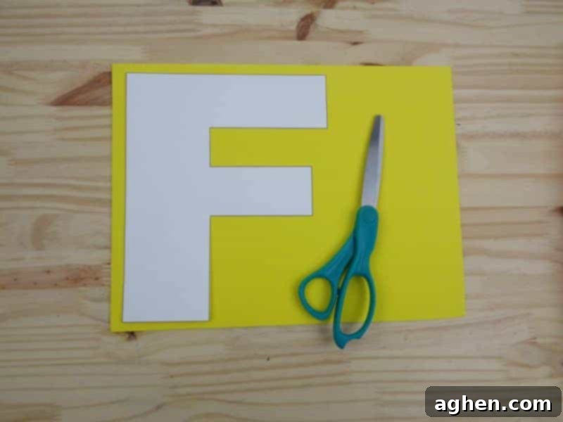 Tracing the cutout Letter F paper template onto a yellow sheet of craft foam using a black marker.