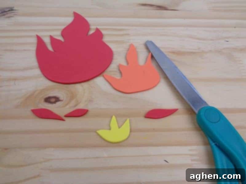 Tracing the fire flame shapes from the printable template onto red and orange craft foam, then cutting them out.