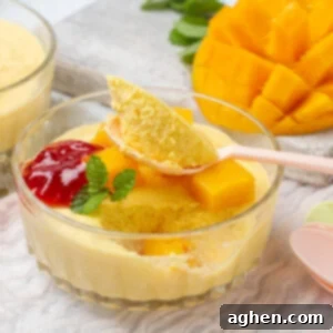 Yellow mango mousse sitting in a clear bowl with a spoon.
