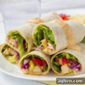 Five chipotle ranch grilled chicken burritos on a plate with a glass of water beside it.