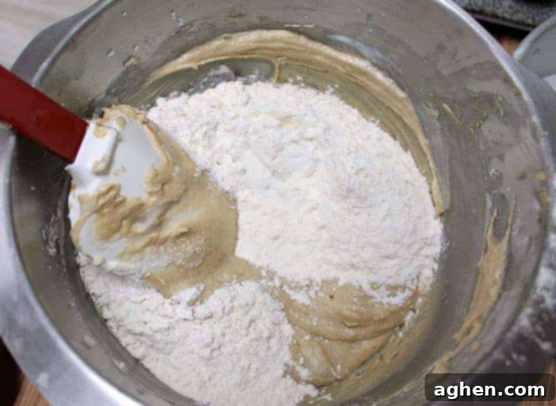 Half of the dry ingredients being stirred into the cake batter by hand.