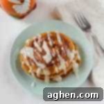 Small square image of stacked pumpkin spice pancakes with cinnamon swirls and cream cheese glaze.
