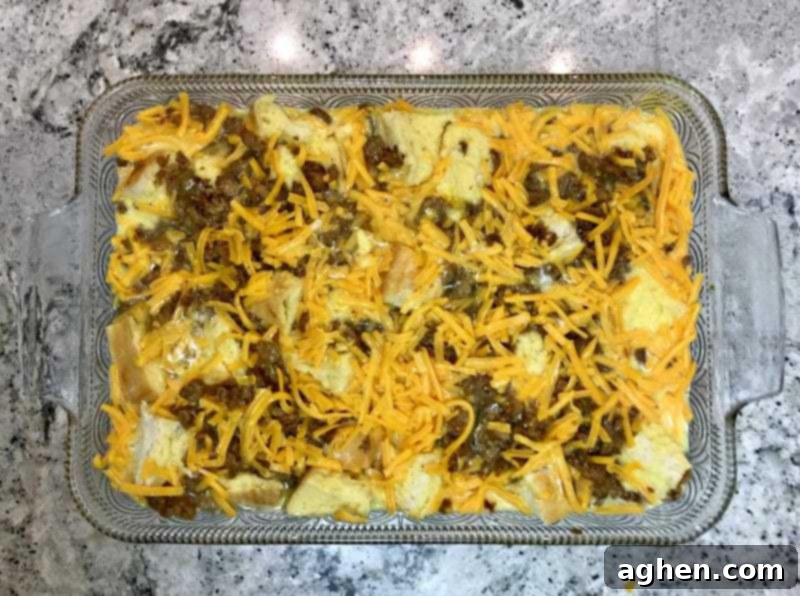 Layers of bread, MorningStar Farms Grillers Crumbles, and cheese in the baking dish before adding the egg mixture.