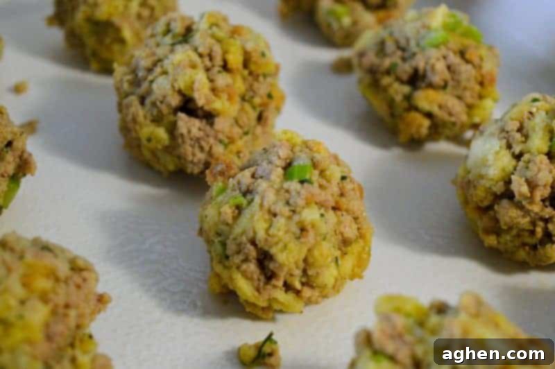 Hands forming uniform quarter-cup size Turkey and Stuffing Balls on a grease-lined baking pan