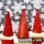 Santa hat cupcakes are made by topping cupcakes with red sugar cones and a mini marshmallow. These fun and easy Christmas cupcakes will definitely be a hit!