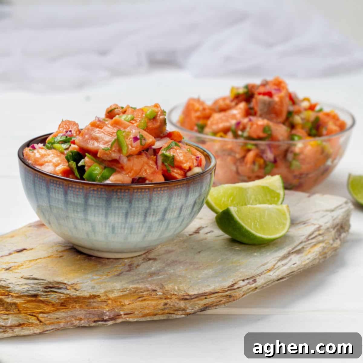 Salmon Ceviche in two bowls with lime wedges.