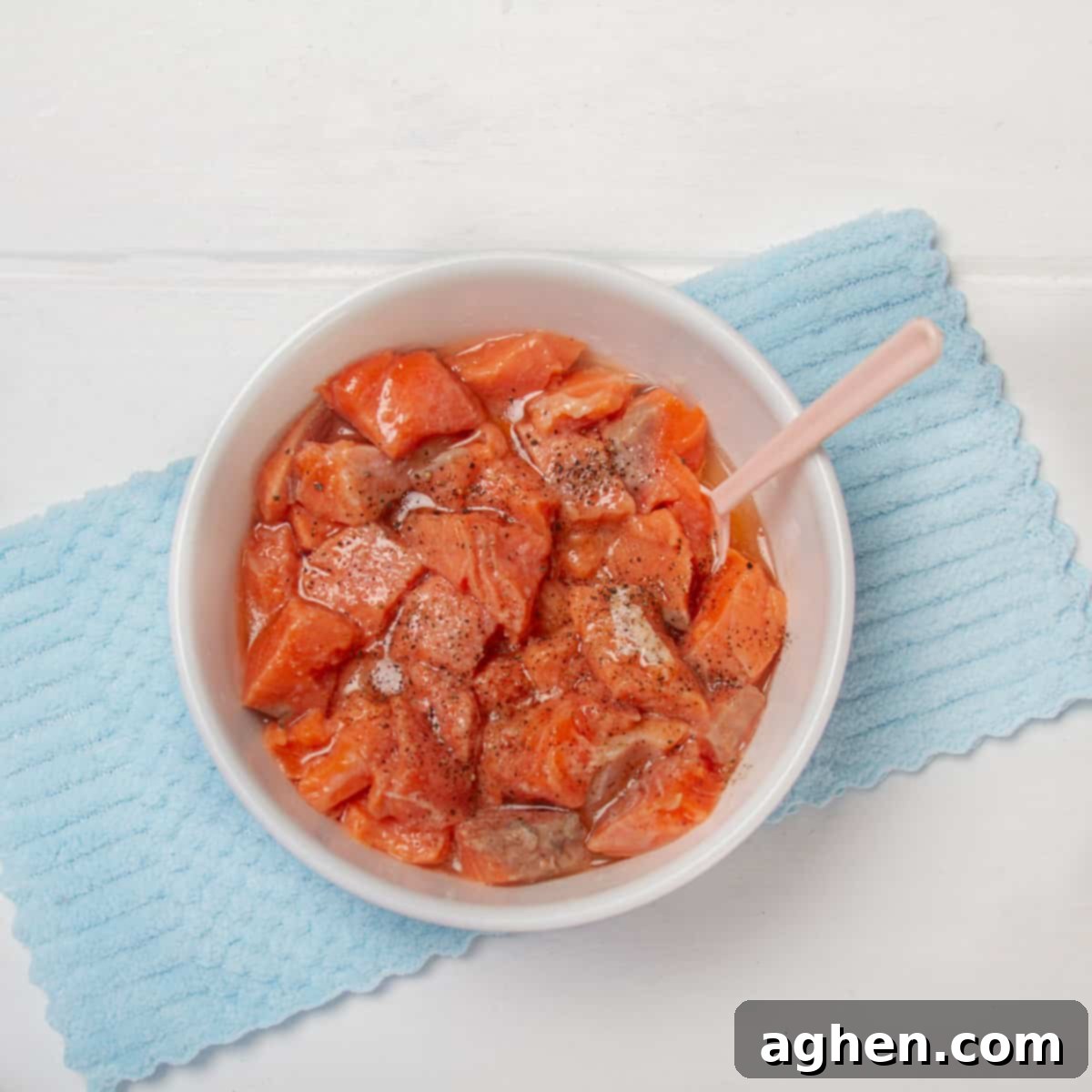 Chunks of fresh salmon coated with lime juice, salt and pepper in a bowl.