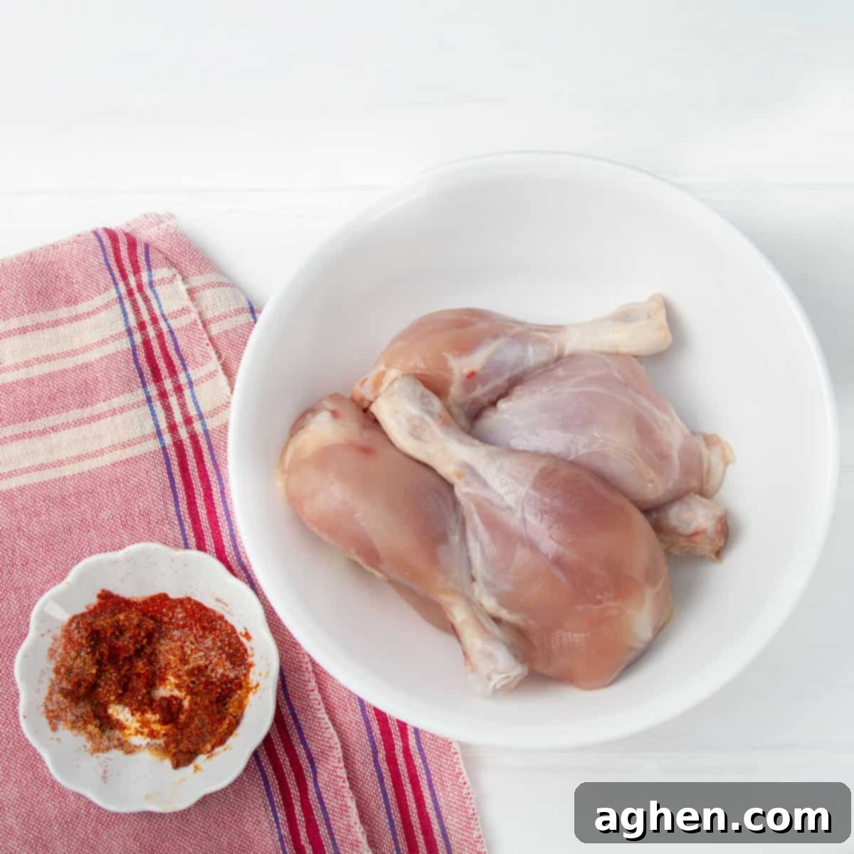 Spice mix of smoked paprika, garlic powder, stevia, salt and pepper in a dish beside raw chicken thighs.