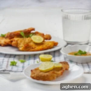 Crispy air fryer chicken cutlets garnished with fresh herbs and lemon slices.
