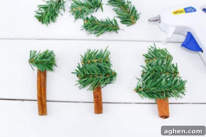 Step 2 of the DIY Christmas tree ornament craft, showing how to glue garland pieces onto a cinnamon stick to form a tree.