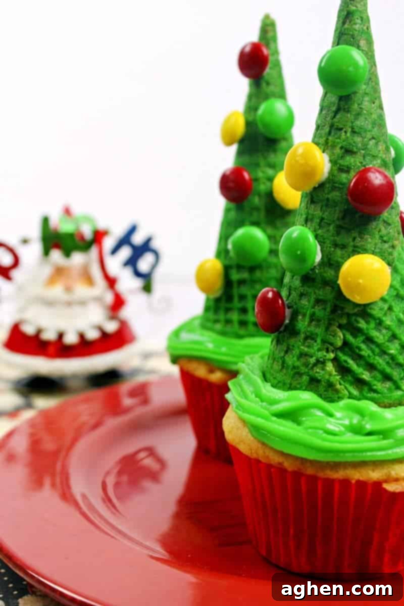 Assembling a tray of Christmas tree ice cream cone cupcakes, each decorated with colorful M&Ms, ready for holiday festivities.
