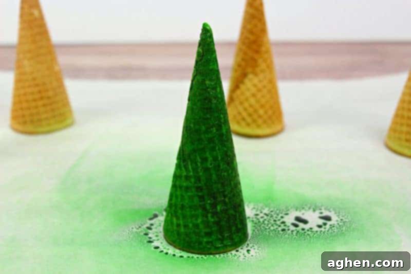 Freshly baked cupcakes frosted with green icing, preparing the base for decorative sugar cone Christmas trees.