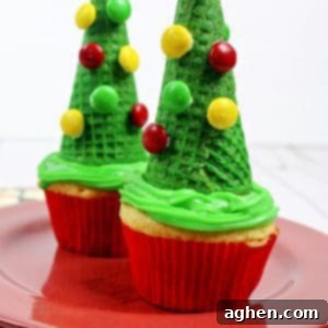 Festive Christmas Tree Cone Cupcakes 8 Delightful Christmas tree sugar cone cupcakes adorned with M&M candies, photographed from a top-down view.